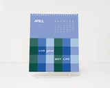 Calendar with blue and green checkered pattern and motivational text on a white background