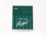 Green stripe calendar with 'Take the Risk!' empowering quote text on a white background