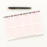 Showgirl Weekly notepad with colorful border and pen on a white background