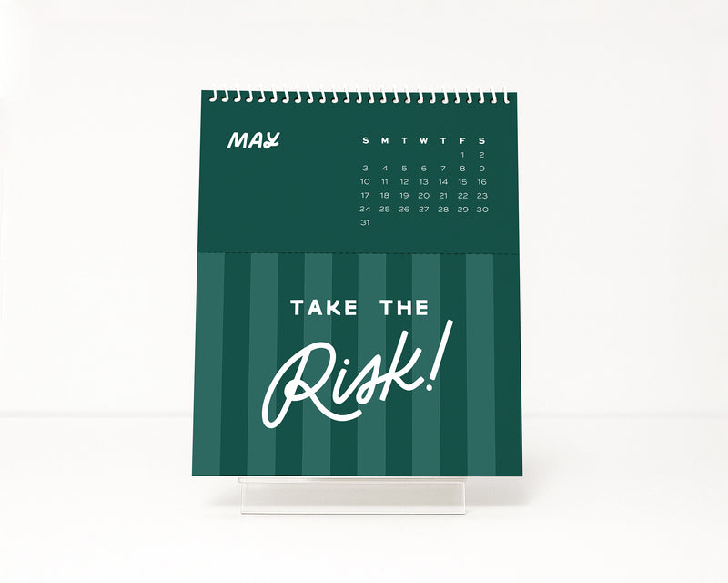 Green stripe calendar with 'Take the Risk!' empowering quote text on a white background